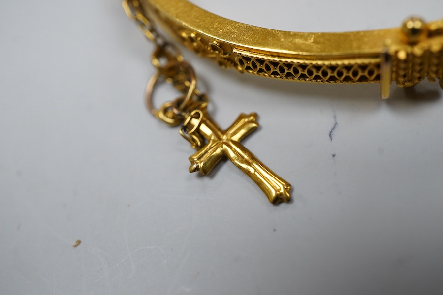 Two Victorian gold bangles, late 19th century, each of hinged design, with rope twist decoration, one later set with a carré-cut diamond, the other suspending a cross from a safety chain, inner circumferences approximate